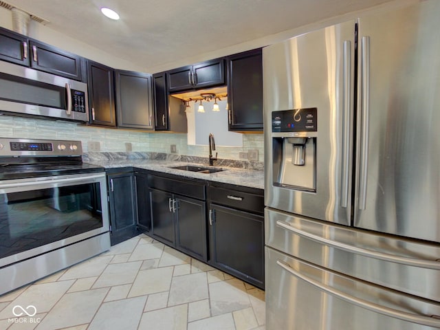 kitchen featuring light stone counters, recessed lighting, stainless steel appliances, a sink, and tasteful backsplash