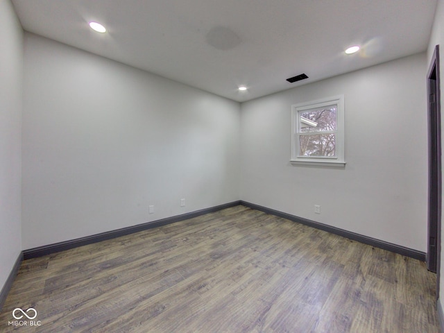 spare room featuring baseboards, wood finished floors, and recessed lighting