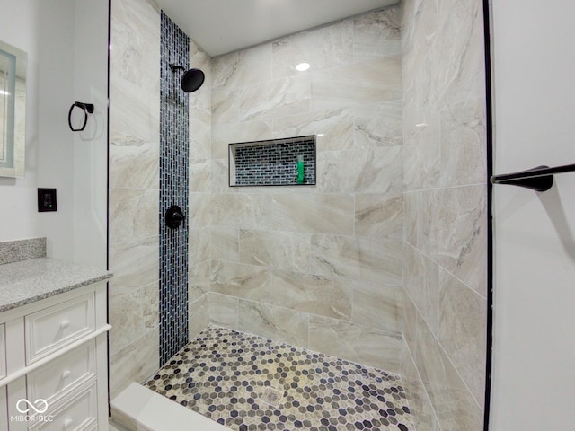 bathroom featuring a tile shower and vanity