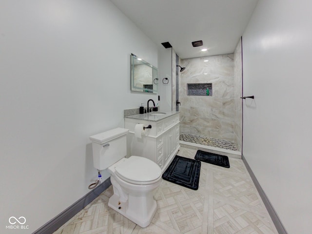 full bathroom with baseboards, a tile shower, vanity, and toilet