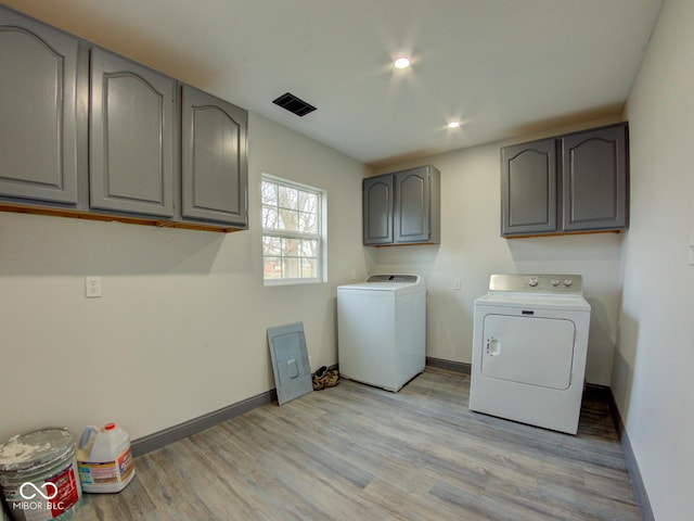 washroom featuring washer and clothes dryer, visible vents, cabinet space, light wood-style flooring, and baseboards