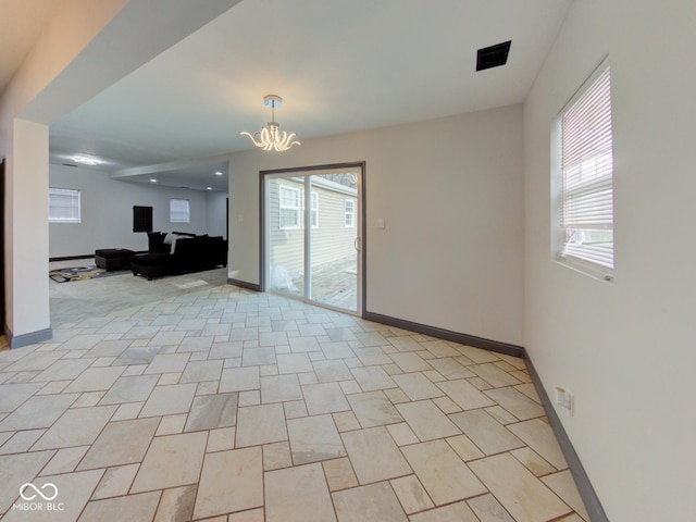 interior space featuring baseboards, plenty of natural light, and an inviting chandelier