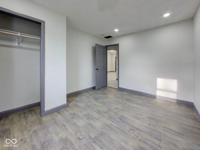 unfurnished bedroom with a closet, recessed lighting, wood finished floors, and baseboards