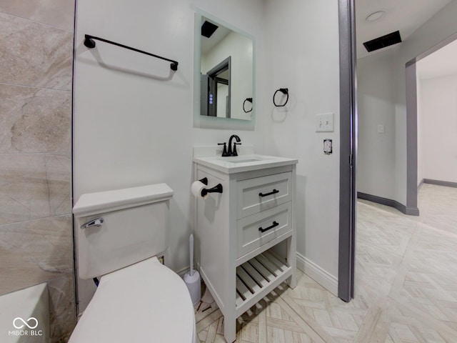 bathroom featuring vanity, toilet, and baseboards