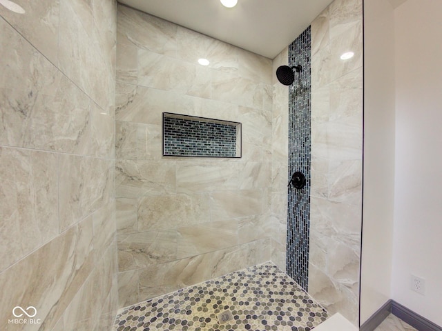 full bath featuring tiled shower and baseboards