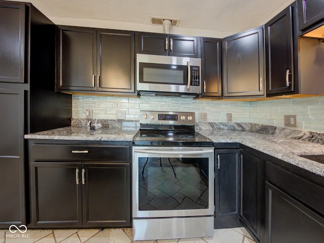 kitchen with light stone counters, appliances with stainless steel finishes, backsplash, and visible vents