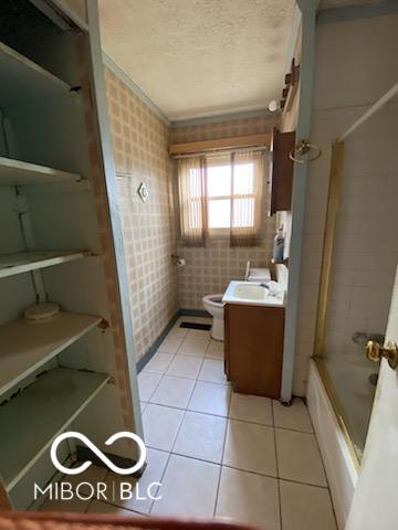 full bath featuring a textured ceiling, tile patterned flooring, toilet, vanity, and tub / shower combination