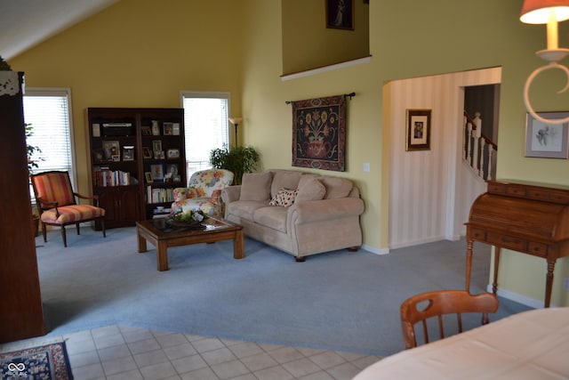 carpeted living area featuring stairway, baseboards, high vaulted ceiling, and a wealth of natural light