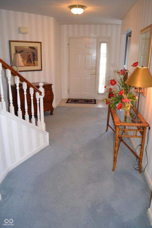 foyer featuring wallpapered walls, carpet, and stairs