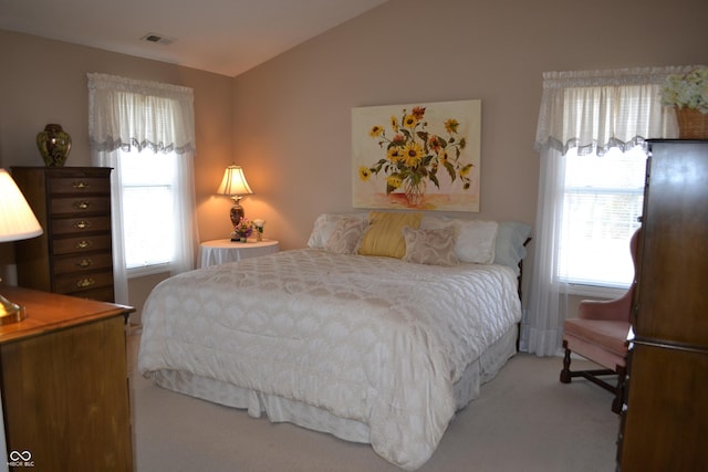 carpeted bedroom with visible vents and vaulted ceiling