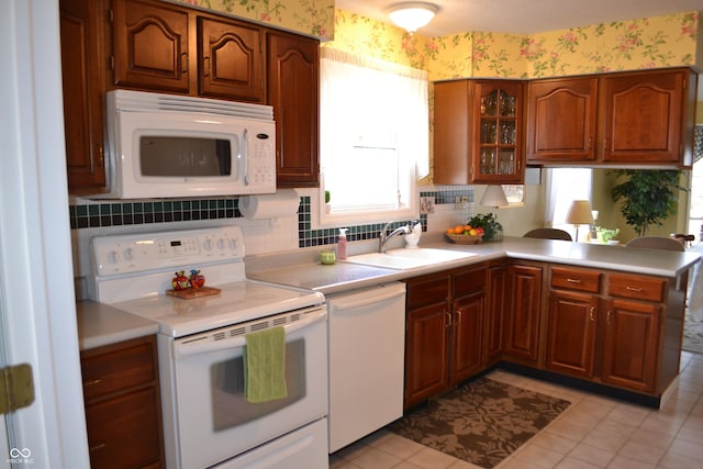 kitchen with light countertops, white appliances, a sink, and wallpapered walls