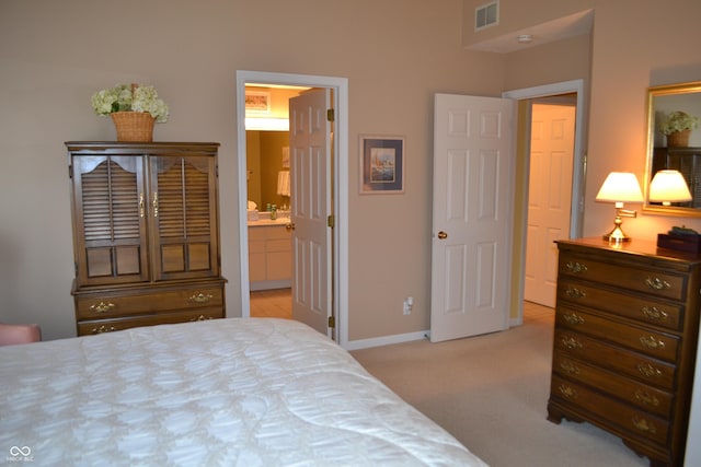 bedroom featuring ensuite bathroom, baseboards, visible vents, and light colored carpet