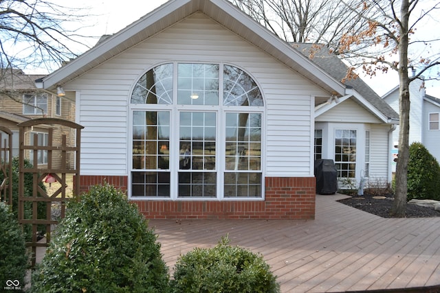 rear view of house featuring a wooden deck, roof with shingles, and brick siding