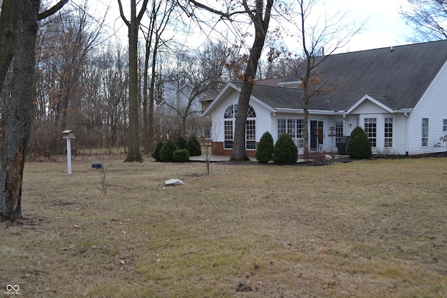 view of front facade featuring a shingled roof, brick siding, and a front lawn