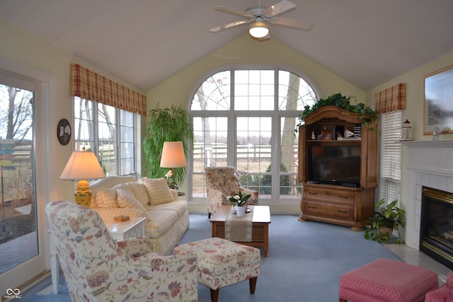 living area featuring lofted ceiling, carpet, a ceiling fan, and a tile fireplace