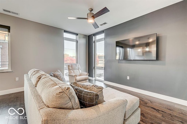 living area with dark wood-style floors, a healthy amount of sunlight, visible vents, and baseboards