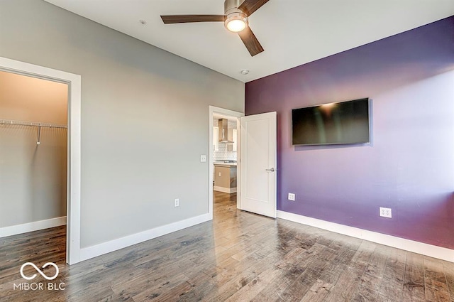 unfurnished bedroom featuring a closet, baseboards, wood finished floors, and a ceiling fan