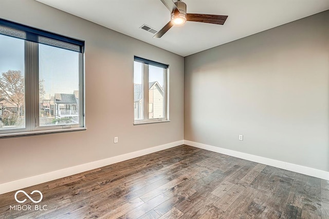 spare room with visible vents, baseboards, a ceiling fan, and dark wood-style flooring