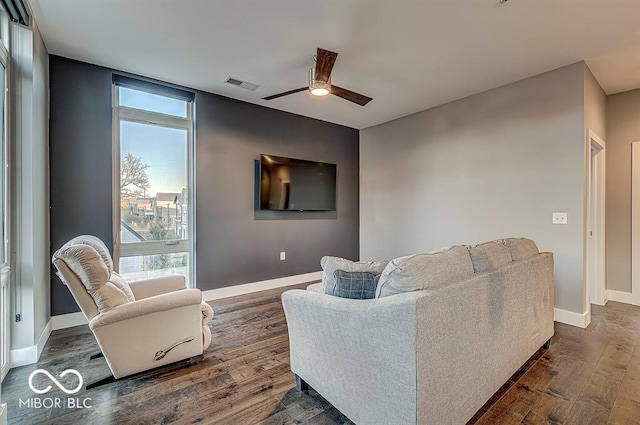 living area featuring a ceiling fan, dark wood-style floors, visible vents, and baseboards