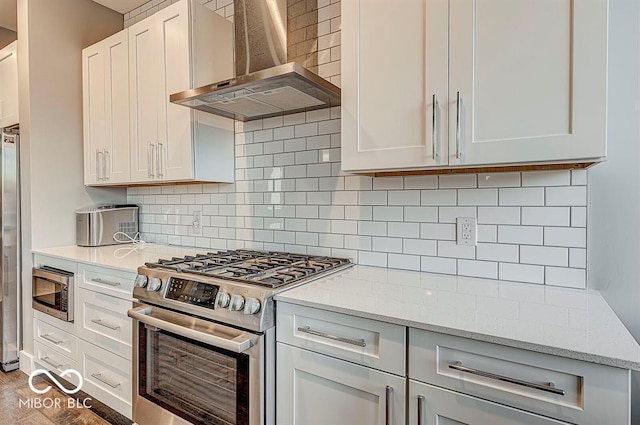 kitchen featuring stainless steel appliances, light stone countertops, backsplash, and wall chimney exhaust hood