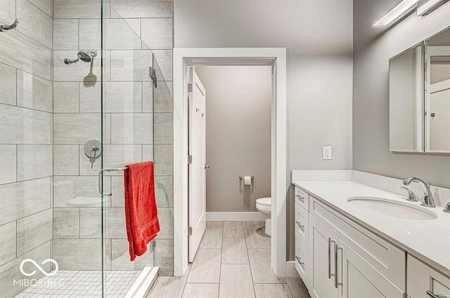 bathroom featuring vanity, a shower stall, toilet, and baseboards