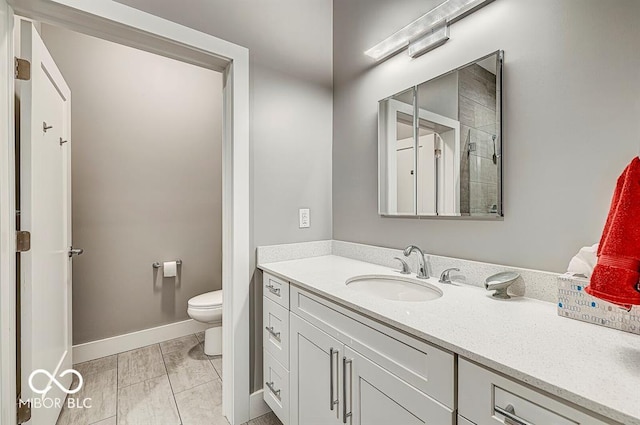 bathroom featuring vanity, toilet, and baseboards