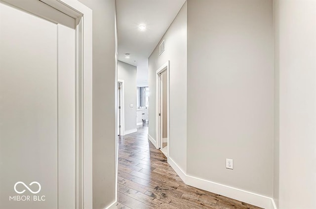 hallway with visible vents, baseboards, and light wood-style floors