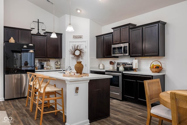 kitchen with dark wood-style flooring, stainless steel appliances, lofted ceiling, light countertops, and dark brown cabinetry