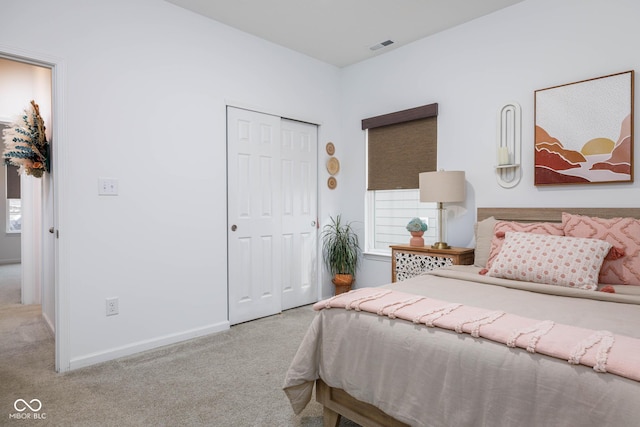 bedroom with a closet, carpet flooring, visible vents, and baseboards