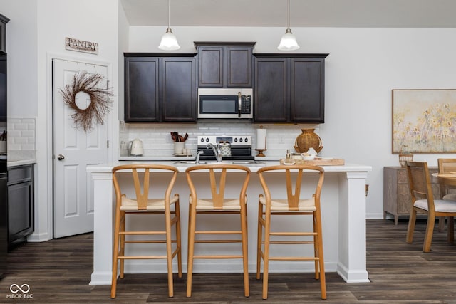 kitchen featuring backsplash, appliances with stainless steel finishes, light countertops, and dark wood-type flooring