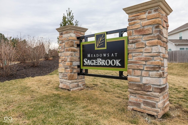 community / neighborhood sign with fence and a yard