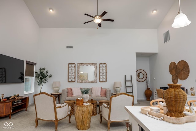 living area with light carpet, ceiling fan, a high ceiling, and visible vents