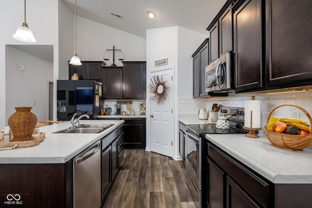 kitchen featuring appliances with stainless steel finishes, vaulted ceiling, a sink, and dark brown cabinets