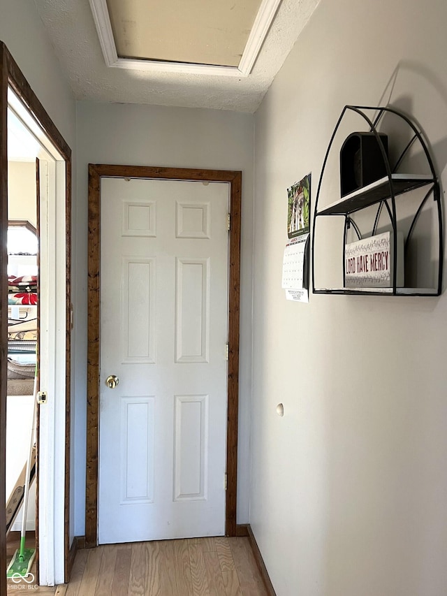 doorway featuring baseboards, a textured ceiling, and light wood finished floors