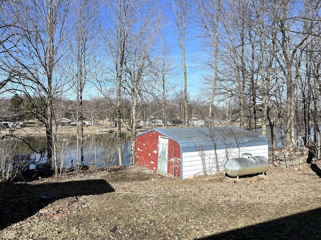 view of yard featuring a water view, an outdoor structure, and a shed