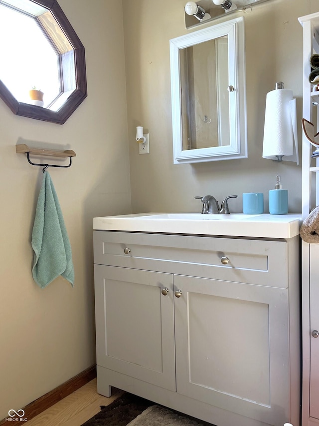 bathroom with wood finished floors, vanity, and baseboards