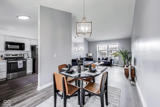 dining space with baseboards, wood finished floors, and a notable chandelier