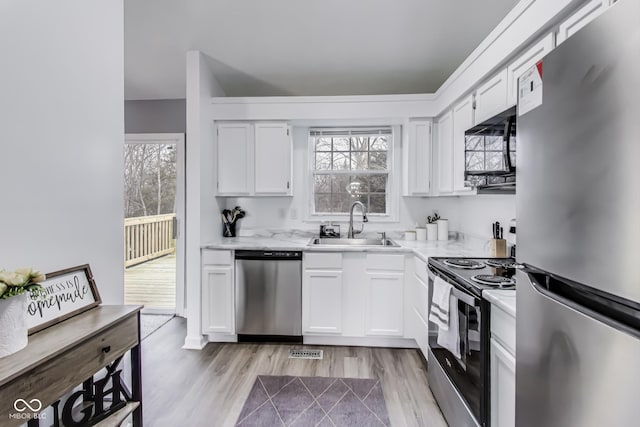 kitchen with light wood finished floors, visible vents, appliances with stainless steel finishes, white cabinetry, and a sink