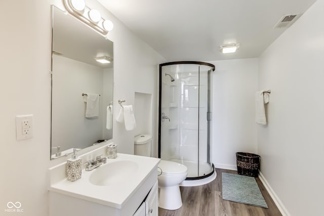 bathroom featuring visible vents, toilet, a stall shower, vanity, and wood finished floors