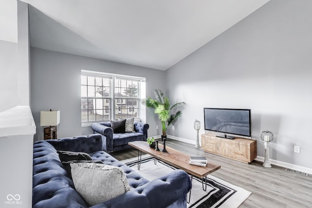 living area featuring vaulted ceiling, wood finished floors, and baseboards