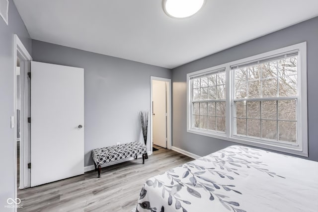 bedroom featuring multiple windows, baseboards, and wood finished floors