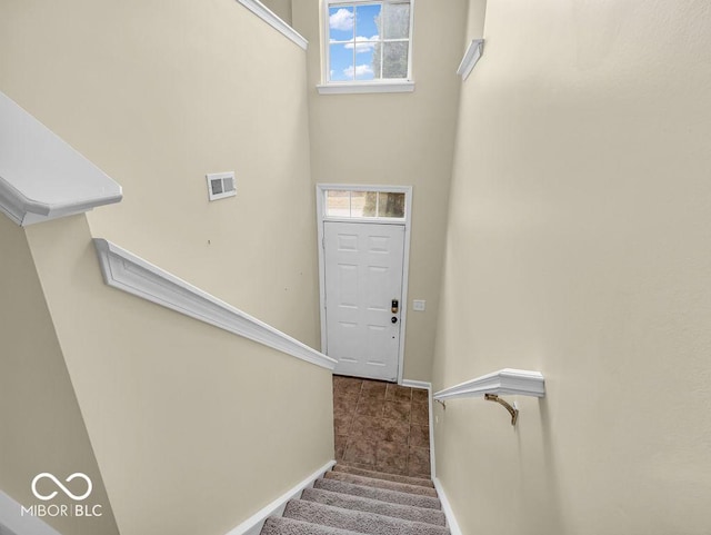 stairway with carpet, plenty of natural light, visible vents, and baseboards