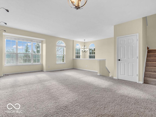 carpeted spare room featuring baseboards, stairway, and a notable chandelier