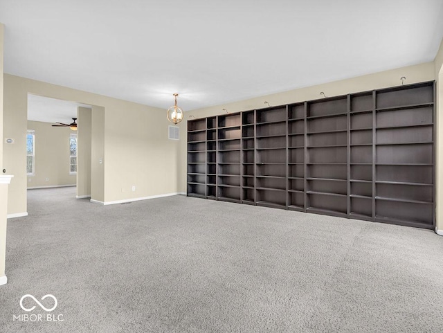 carpeted spare room featuring ceiling fan, built in features, visible vents, and baseboards