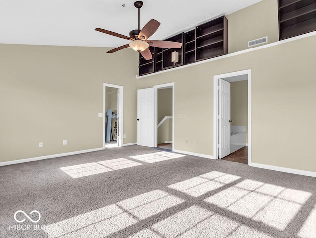 unfurnished bedroom with baseboards, visible vents, ensuite bathroom, carpet floors, and high vaulted ceiling