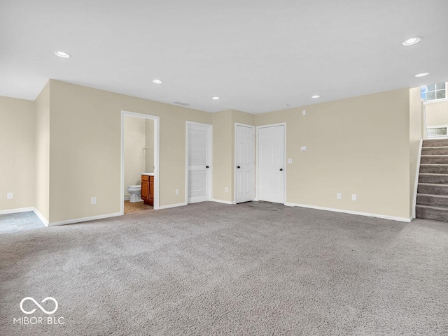 unfurnished living room featuring carpet, visible vents, and stairs