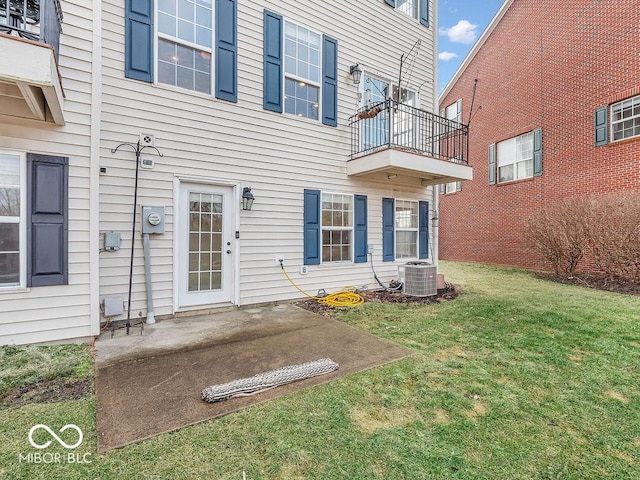 entrance to property with a balcony, a patio area, central AC, and a lawn