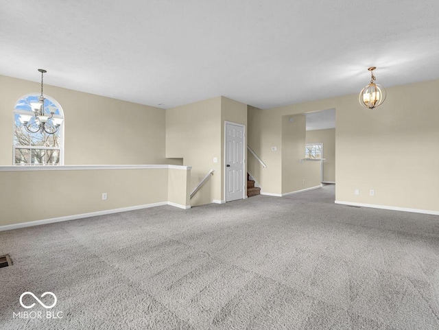 carpeted empty room with visible vents, baseboards, and a notable chandelier