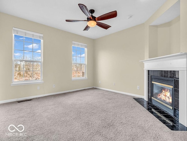 unfurnished living room featuring dark colored carpet, baseboards, ceiling fan, and a tiled fireplace