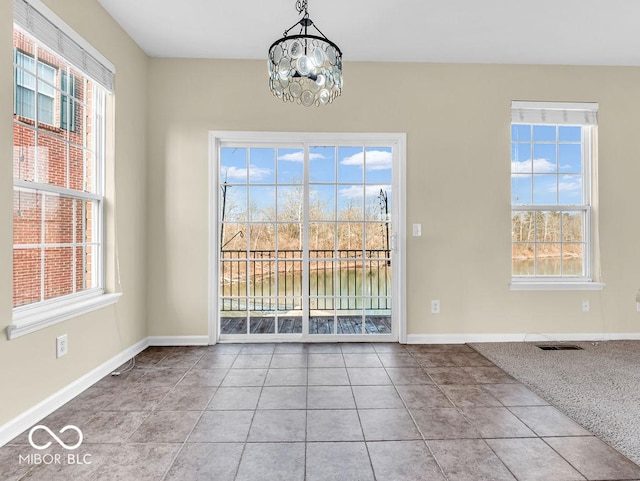 unfurnished dining area with baseboards, plenty of natural light, visible vents, and tile patterned flooring